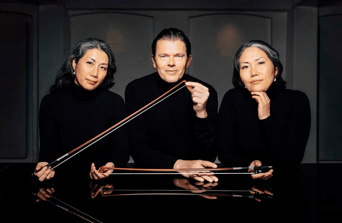 Portrait of three musicians posing in Mogens Dahl Concert Hall, which offers chamber concerts and classical music experiences. The image highlights their professional demeanor in front of an elegant concert hall that features everything from classical masterpieces to innovative compositions.