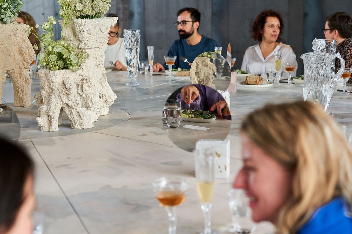 Guests enjoying an elegant dinner at a festive table during an event at Mogens Dahl Concert Hall, with a focus on a sophisticated and relaxed atmosphere.