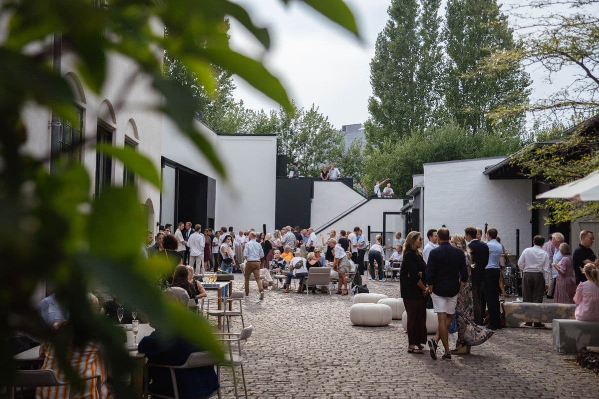 The courtyard filled with guests during an event at the Garage at Mogens Dahl Concert Hall. The image shows the busy and festive outdoor area where participants are enjoying the event. The lively atmosphere in the courtyard highlights the Garage's ability to create an inviting and social experience for events.