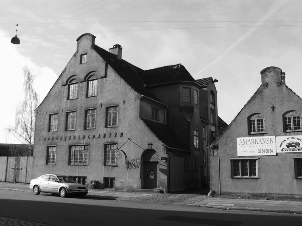 Black-and-white image of the building's exterior from an earlier time, before it became Mogens Dahl Concert Hall. The photo shows the historical building, which previously housed a stable, caretaker's residence, garage, and auto painter, before being converted into the concert hall at Islands Brygge. The image illustrates the building's original architecture and history.